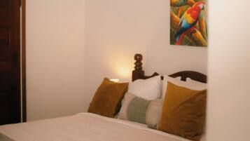 A bedroom with a bed, pillows, a painting, and a door.