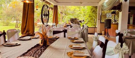 A long dining table with white chairs, set for a meal.