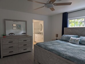 A bedroom with a bed, dresser, vanity, and a ceiling fan. - Siesta Breeze (Sarasota)