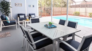 A covered outdoor area with a pool, white furniture, and a ceiling fan. - Siesta Breeze (Sarasota)