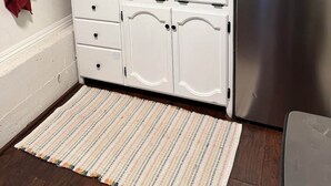A kitchen with a stainless steel refrigerator, a sink, a coffee maker, and a striped rug.