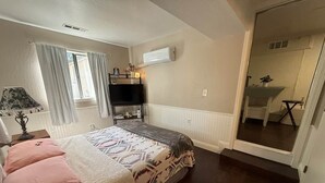 A bedroom with a bed, bedside table, lamp, and a mirror.