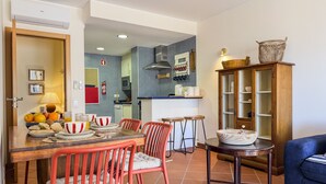 Eine moderne Küche mit gefliestem Rücksprüher, ein Essbereich mit Holztisch und roten Stühlen sowie ein blaues Sofa im Wohnzimmer.