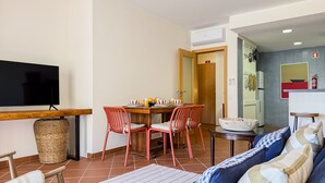 Ein Wohnzimmer mit Fernseher, Esstisch, Stühlen, einer Couch und einem Deckenventilator.