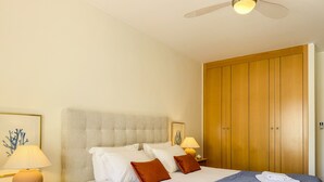 Ein Hotelzimmer mit einem Bett, einem Nachttisch mit Lampe, einem Kleiderschrank und einem Deckenventilator.