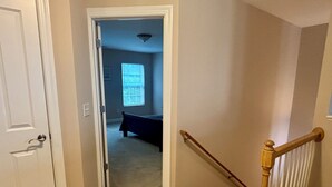 A hallway leading to a bedroom with a bed, a door, and a staircase. - Pet friendly 3-bedroom townhome walking distance to charming downtown Aiken (Aiken)