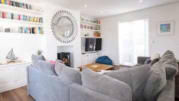 Una sala moderna con un sofá modular gris, una chimenea, una estantería y un espejo grande.