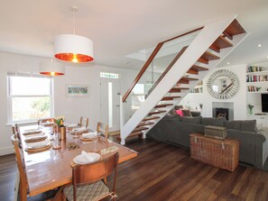A modern interior with a dining area, staircase, and living space. - Lorrell (Salcombe)