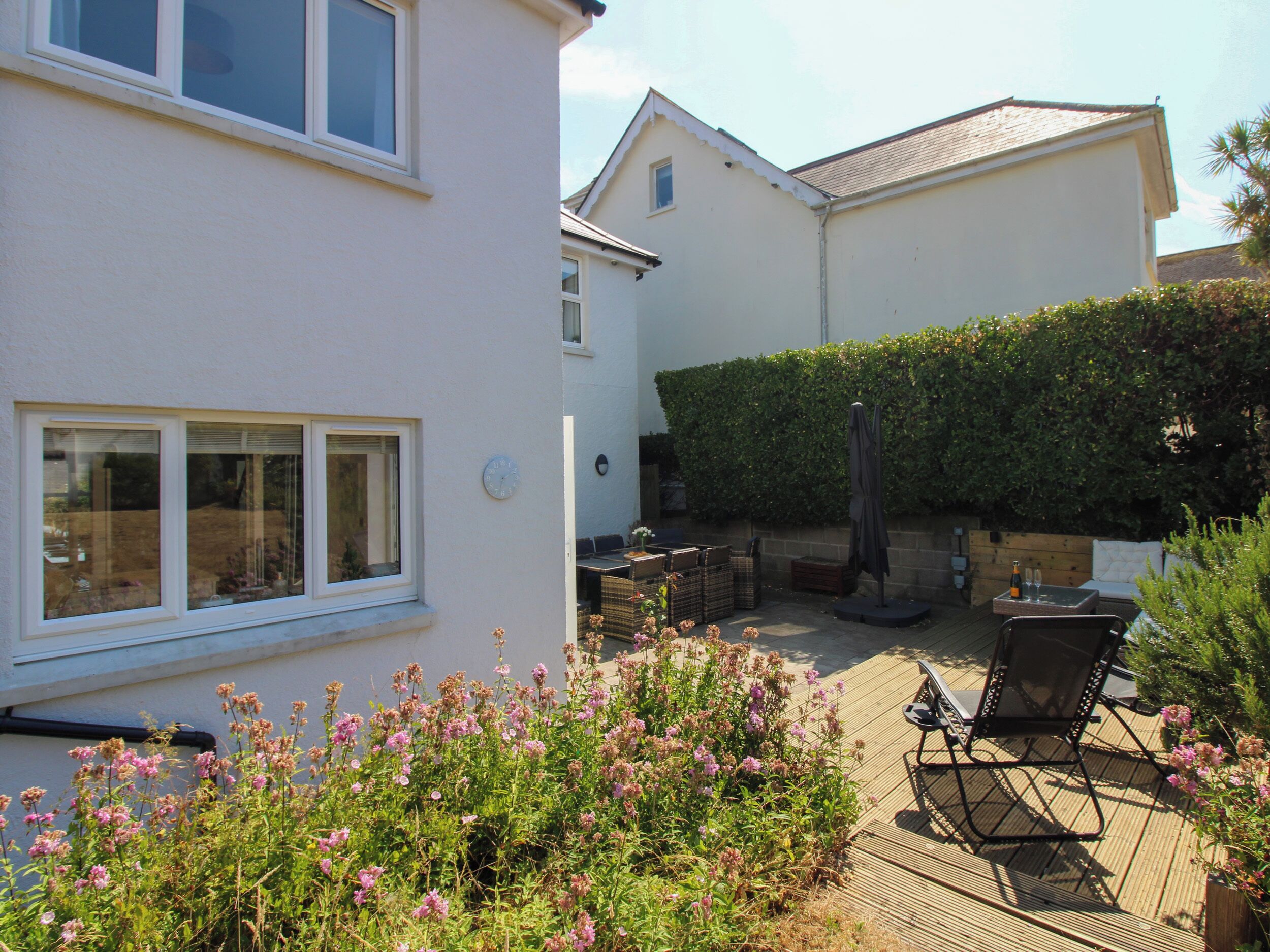 A residential property with a patio area, outdoor seating, and a garden with flowering plants.
