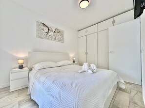A bedroom with a bed, nightstands, a wardrobe, and a wall art piece. - Yomely Towers - Y4G (Playa de las Américas)
