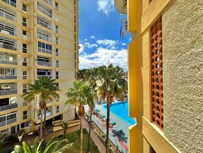 A high-rise building with balconies, a swimming pool, and palm trees. - Yomely Towers - Y4G (Playa de las Américas)