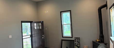 A living room with a sofa, a coffee table, a door with a window, and a large mirror.