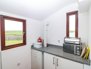 Eine kleine Küche mit Blick ins Freie, ein Feuerlöscher, ein Toaster und eine Spülmaschine.