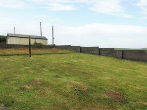 A grassy field with a building and a stone wall. - Faraway (Ty Croes)