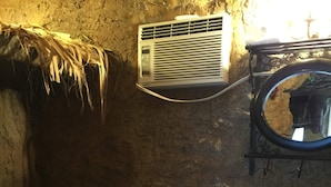 Baño con inodoro, lavamanos, toallero y aire acondicionado de pared.