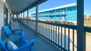 A covered outdoor area with blue chairs and a view of a blue building with balconies. - Perfect family stay by Gulf & Lagoon! Dogs welcome (Gulf Shores)