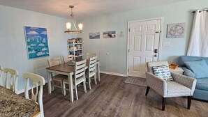 A dining area with a wooden table and chairs, a chandelier, and a bookshelf with books. - Perfect family stay by Gulf & Lagoon! Dogs welcome (Gulf Shores)