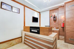 A reception desk with a sign reading 'TOWNHOUSE' and a small television mounted on the wall. - Super Townhouse Chhatarpur Near Metro Park (New Delhi)