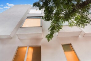 A building with multiple windows and a tree branch extending over the structure. - Super Townhouse Chhatarpur Near Metro Park (New Delhi)