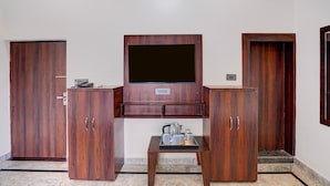 A room with a wooden cabinet, a television mounted on the wall, and a small table with cups. - Classic Ummed Palace (Mathura)