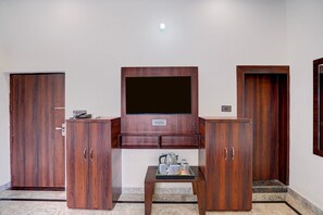 A room with a wooden cabinet, a television mounted on the wall, and a small table with cups. - Classic Ummed Palace (Mathura)