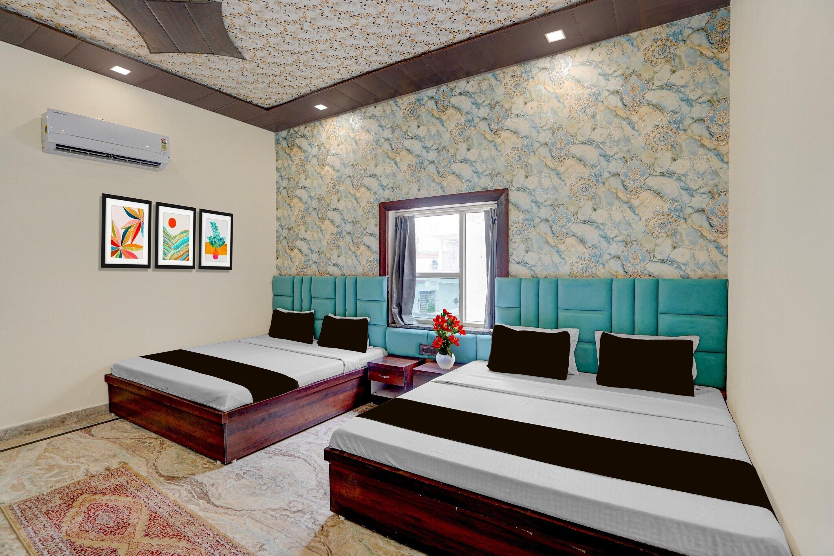 Habitación de hotel con dos camas, una ventana y un detalle decorativo en la pared.