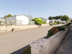 Rua residencial com casas, céu claro e calçada de concreto.