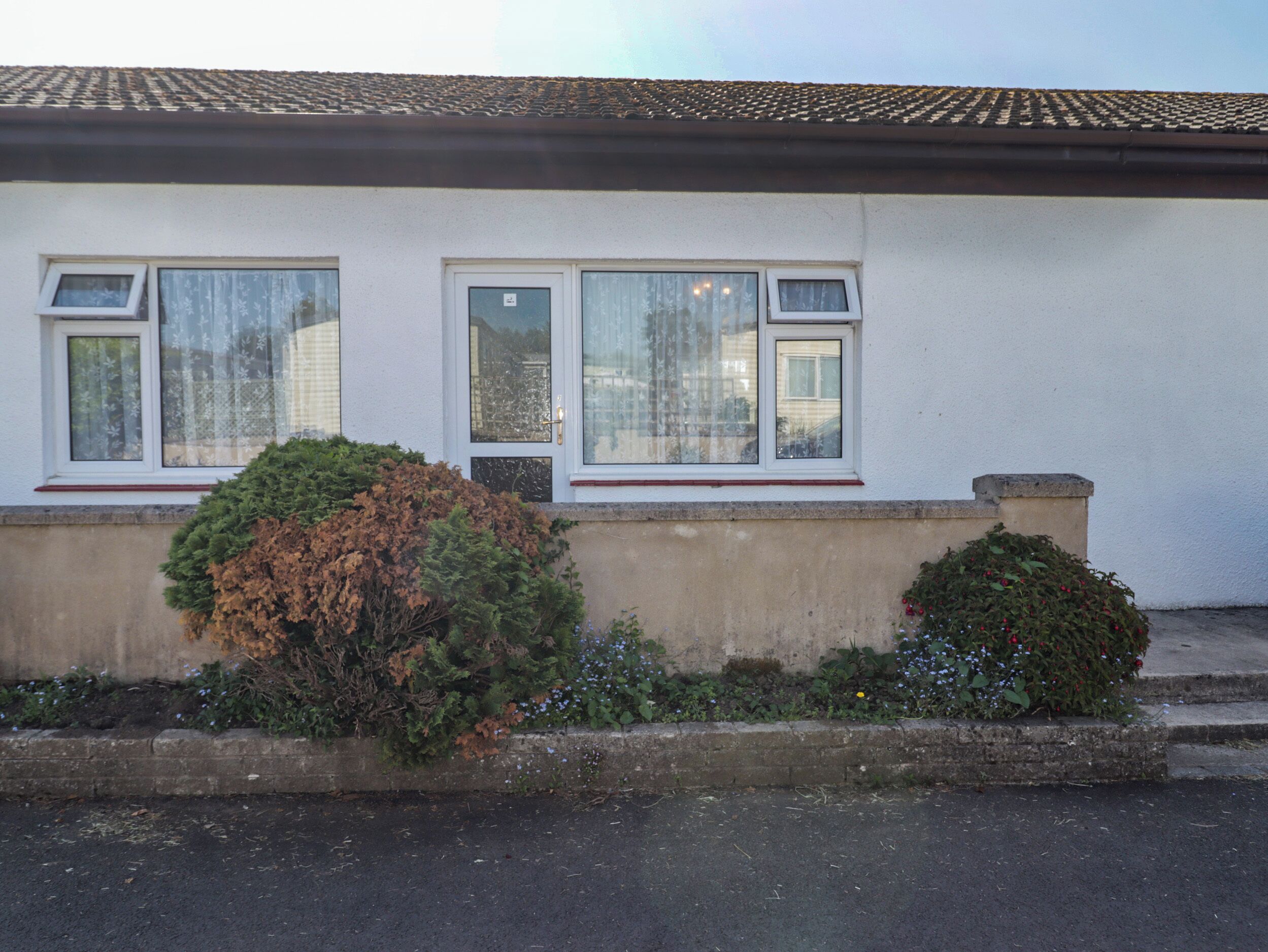 A building with two windows, a tiled roof, and a concrete base.