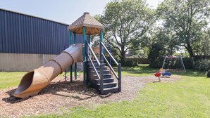Ein Spielplatz mit Rutsche, Treppe und Schaukeln.