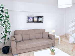 A modern living room with a beige sofa, a potted plant, a framed triptych, and a white coffee table. - Casa Miriam Apartment (Los Cristianos)