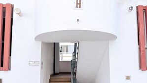 Un immeuble à plusieurs étages, doté d’un escalier central, d’un panneau en forme de « H » bien visible et d’une porte située au pied de l’escalier.