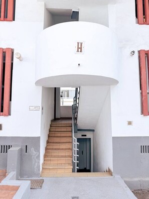 A multi-level building with a central staircase, a visible 'H' sign, and a door at the bottom of the stairs. - Casa Miriam Apartment (Los Cristianos)