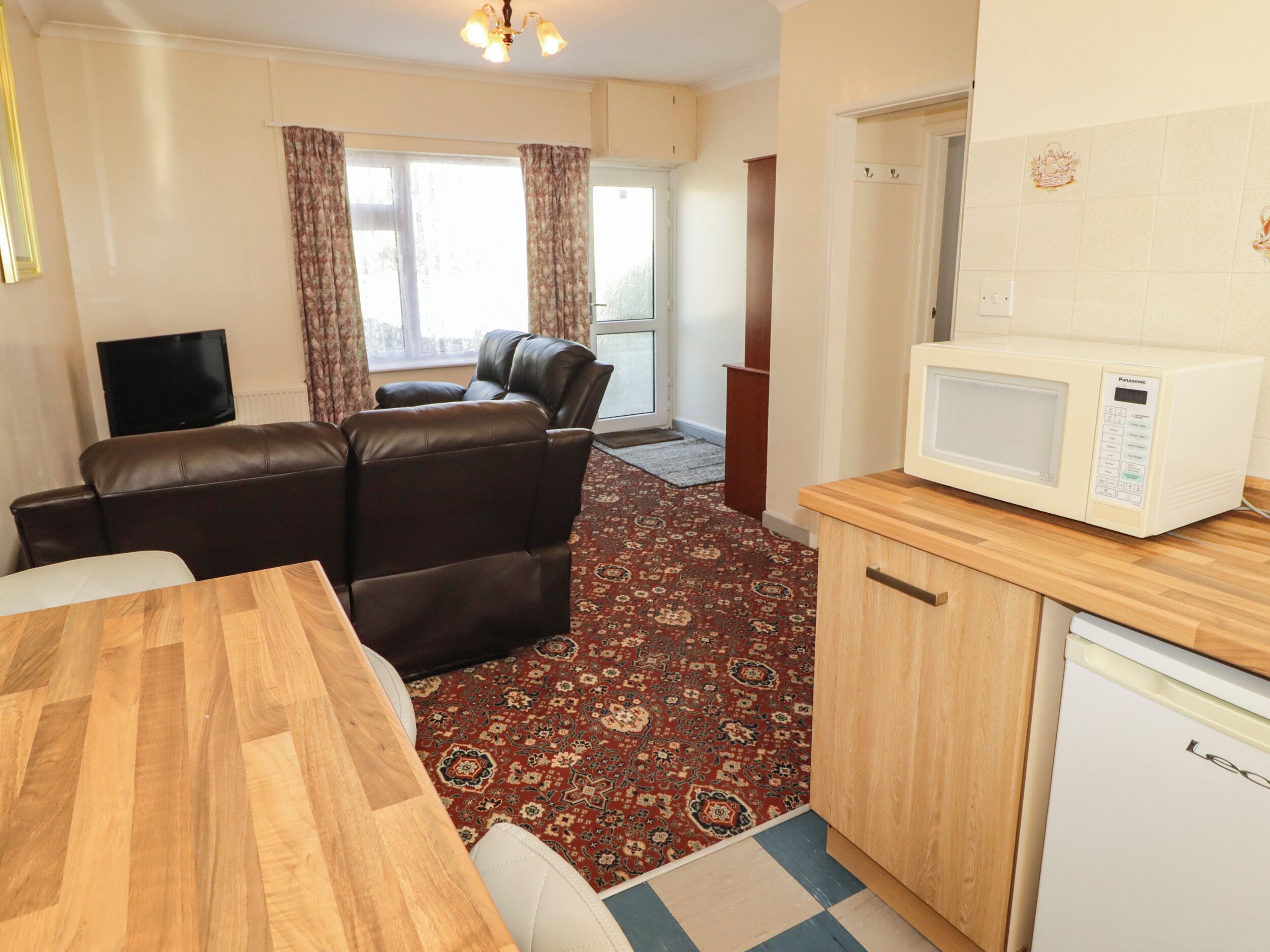 A compact living space with a sofa, a television, a microwave, and a refrigerator.