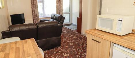 A compact living space with a sofa, a television, a microwave, and a refrigerator.