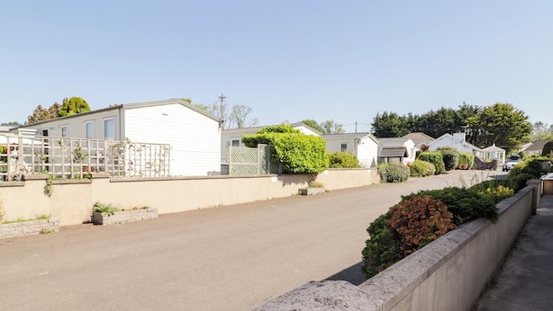 A residential street with houses, a clear sky, and a concrete sidewalk. - Cottage 1 (Tenby)