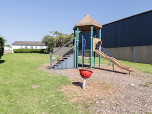 A playground with a slide, climbing steps, and a small shelter. - Cottage 1 (Tenby)