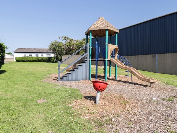 A playground with a slide, climbing steps, and a small shelter. - Cottage 1 (Tenby)