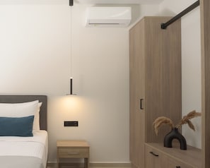 Ein Schlafzimmer mit Bett, Nachttisch, Kleiderschrank und Klimaanlage.