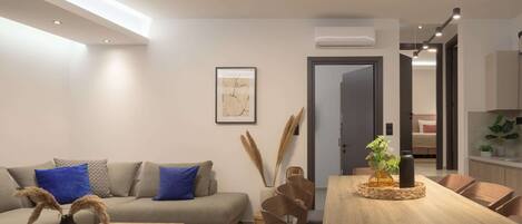 A modern living room with a sofa, coffee table, dining table, and chairs.