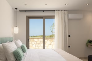 Ein Schlafzimmer mit Bett, einer Hängeleuchte, einem Fenster mit Aussicht und einer Klimaanlage.