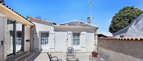 A patio area with a table and chairs, a covered seating area, and a building with a tiled roof and a chimney.