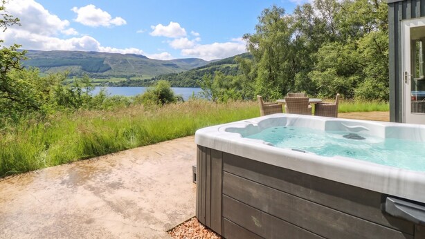 Un jacuzzi con vista a un lago y colinas.
