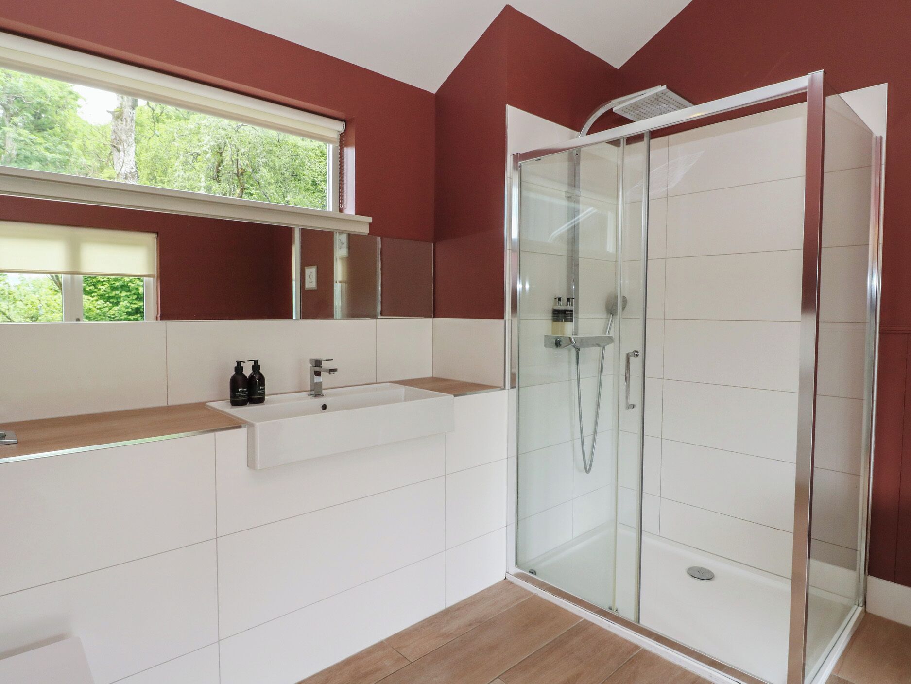 A modern bathroom with a glass-enclosed shower, a white sink, and a mirror above it.
