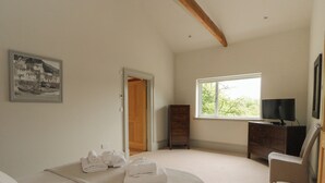 Un dormitorio con cama, cómoda, televisor y ventana con vistas.