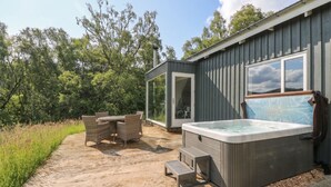 Hidromasaje, mobiliario exterior y una puerta de cristal que da a una zona cubierta.