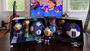 Ein Zimmer mit Fernseher, der ein Sportereignis zeigt, einem Pokal und Stofftieren auf einem Tisch.