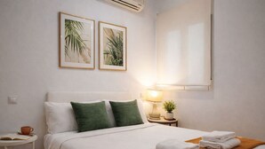 A hotel room with a bed, pillows, a nightstand with a lamp, a small table, and two framed pictures on the wall. - 8-guest Malasana Central Suite (Madrid)
