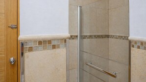 A shower with a glass door, a wooden door, and tiled walls. - 8-guest Malasana Central Suite (Madrid)