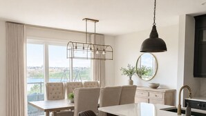 Uma cozinha moderna com área de bar, mesa de jantar com cadeiras e uma grande janela com vista.