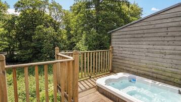 A wooden deck with a hot tub and a wooden building.